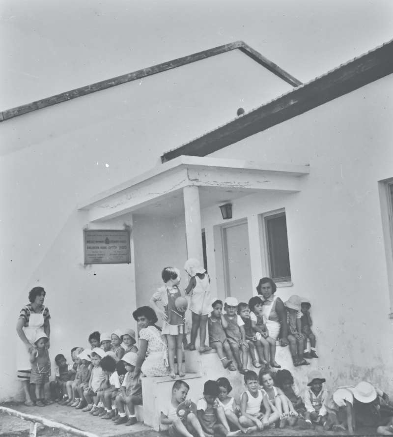 Group of  children and adults in front of building